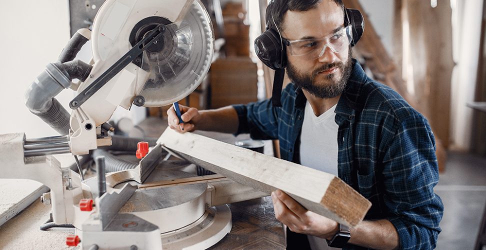 Wood cutting with circular saw. Closeup of mature man sawing lumber.