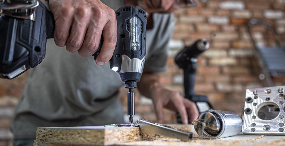 Screwing a self-tapping screw into a metal fastening hole on a wood strip using a screwdriver, the work of a carpenter.